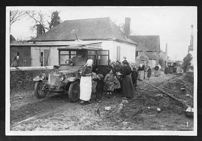 Occupants of a British motor car stop to give the inhabitants of a newly ...