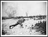 Thumbnail of file (63) N.495 - To save himself from the flying shrapnel of the two high explosive shells that have burst near, this Tommy has flung himself flat on the ground