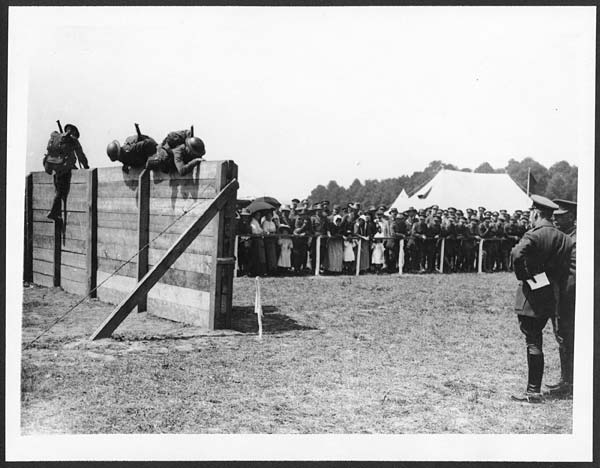 (67) D.1709 - H.M. watching full packed infantrymen going over a wall at the sports held by the Australians
