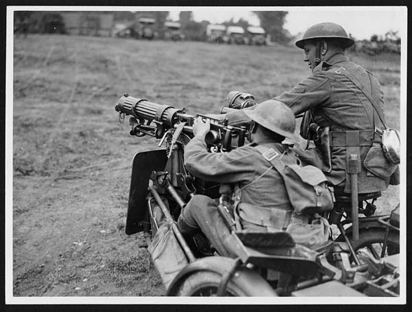 (125) L.776 - Motor machine gunner in France fixing a belt of ammunition to his gun
