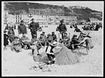 N.420British, French and American soldiers seated with W.A.A.C.s on the sands watching French kiddies building sand castles